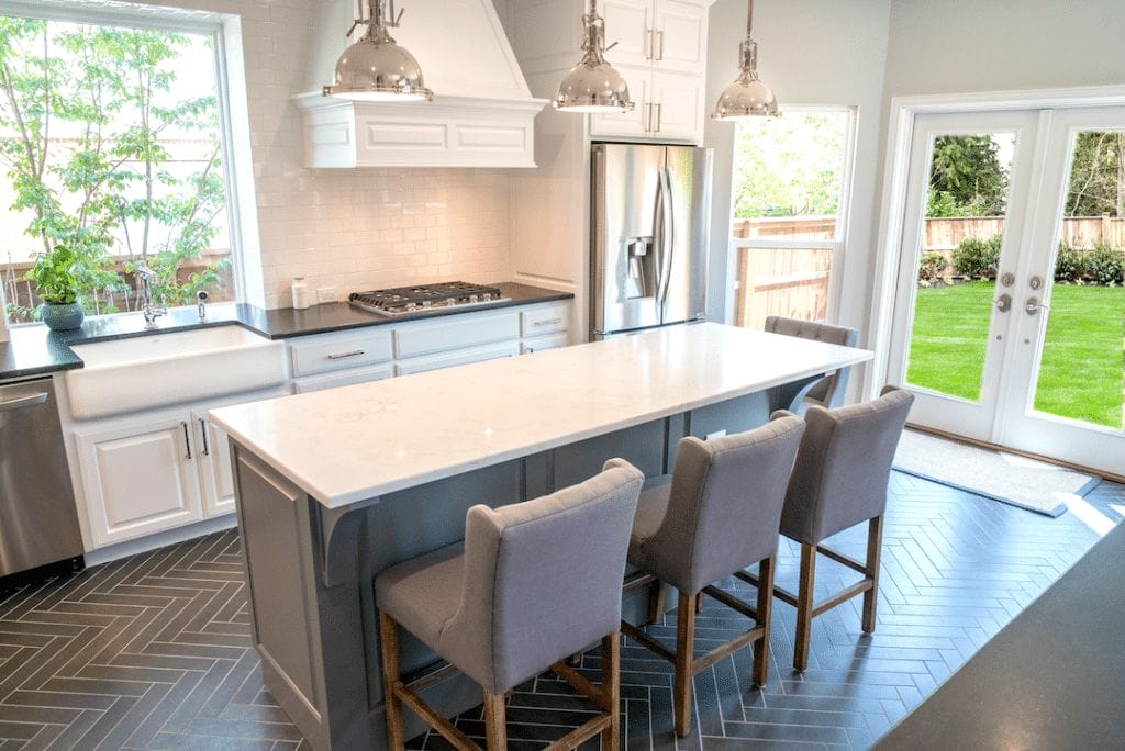 Custom white kitchen with gray island and herringbone floor.